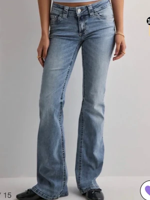 Ljusblå bootcut jeans från Nelly - Säljer ett par ljusblå bootcut jeans från Nelly med klassiska kontrastsömmar och snygga fickdetaljer bak med vita knappar. Jeansen har låg midja och är tillverkade i denim med lätt stretch för skön passform. De är helt slutsålda på hemsidan!!💗💗