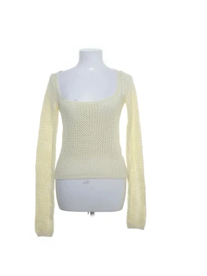 Ljusgul stickad tröja med vid ringning - Trendig ljusgul stickad tröja med lång ärm och bred, fyrkantig ringning. Tröjan har ett genombrutet stickmönster som ger en luftig känsla och sitter figurnära. Perfekt att styla lager på lager för en cool look.