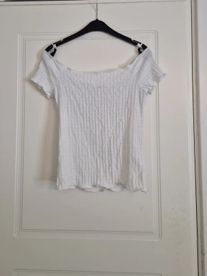 Vit offshoulder ribbad topp - Trendig vit offshoulder topp med ribbad struktur. Tunn och stretchig, perfekt för varma dagar. Snygg att styla med både jeans och kjol. 