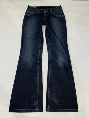 Lågmidjade bootcut jeans från Lee - 📐midja 36 cm rakt över, gren 20 cm och innerben 78 cm. Storlek W27/L31 vilket motsvarar S enligt google❤️Jag är xs och 170 för referens Uppskattad storlek: XS. Men det är storleksmärkningen och måtten (mätta på mitt sätt) som gäller om man köper