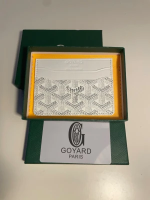 Vit kortfodral från G4yard - Snyggt vitt kortfodral från G4yard med klassiskt mönster och präglad logotyp framtill. Tillverkat i exklusivt läder med flera kortfack och stilren design. Perfekt för dig som vill ha en lyxig och praktisk accessoar i fickan.