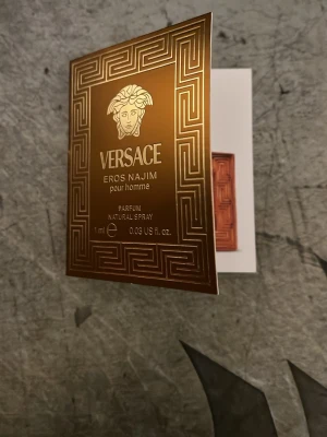 Versace Eros Najim pour homme parfymprov - Exklusiv parfymprov från Versace Eros Najim pour homme. Aromatisk och amberdoft med noter av mandarin, saffran, kardemumma, oud, cederträ, patchouli och vetiver. Provet är 1 ml och kommer i en elegant guldbrun förpackning.