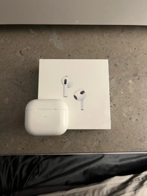 AirPods 3rd generation - Äkta Apple AirPods 3rd generation (se serienummret ) med laddningsetui. Trådlösa hörlurar med bra ljudkvalitet och smidig anslutning till iPhone, iPad och Mac. Laddningsetui och originalförpackning ingår. Viss smuts och mindre slitage syns på etuiet, men hörlurarna är i gott skick.