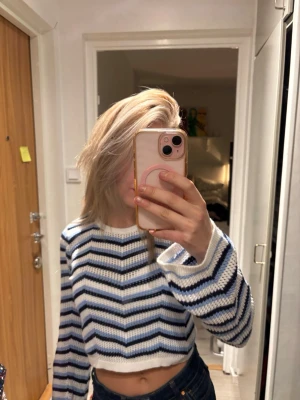 Vit och blå randig stickad croptröja - En stickad croptröja med vita, blå och svarta vågiga ränder. Materialet är mjukt och luftigt, perfekt till en vanlig dag eller en varm sommardag på stranden☀️⛱️ Tröjan är köpt i Italien, och har enbart används ett fåtal gånger💓