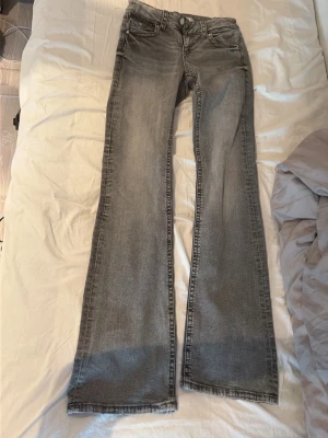 Grå bootcut jeans med utsvängda ben - Säljer ett par grå bootcut jeans från Gina i storlek 164