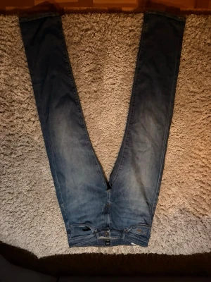 Blå jeans från Hugo Boss - Snygga blå jeans från Hugo Boss med klassisk femficksmodell och brunt läderpatch bak i midjan. Jeansen har raka ben och är gjorda i slitstark denim med kontrastsömmar. Skriv pm för mer info