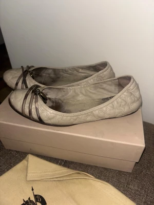  Burberry ballerina shoes - Burberry ballerinaskor i beige med quiltad design och dekorativa detaljer framtill. Skorna har en platt sula och är designade för komfort. Levereras med original skokartong och dustbag.