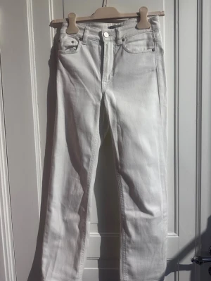 Filippa K vita jeans – XXS - Kritvita jeans från Filippa K i modellen Stella. Smal rak passform med designveck längs baksidan av vaderna.  Mycket fint skick förutom en liten svag fläck på baksida lår enligt bild.  Storlek XXS.  Mått:  * Midja: 31 cm * Ytterbenslängd: 89 cm * Innerbenslängd: 64 cm * Benslut: 17 cm * Midja till gren fram: 24 cm