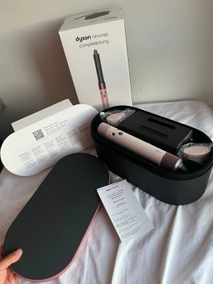 Dyson Airwrap Complete Long hårstyler - Dyson Airwrap Complete Long i roséguld och svart med flera tillbehör. Kommer i en snygg svart förvaringsbox och originalkartong. Perfekt för att styla och forma håret med olika borst- och locktillbehör. Innovativ teknik för enkel hårstyling.
