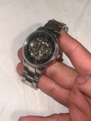 Silverfärgad automatisk klocka - Stilren klocka i silverfärgat metallarmband med genomskinlig urtavla som visar det automatiska urverket. Klockan har en klassisk rund form och detaljerad boett. Perfekt accessoar för dig som gillar mekaniska klockor.