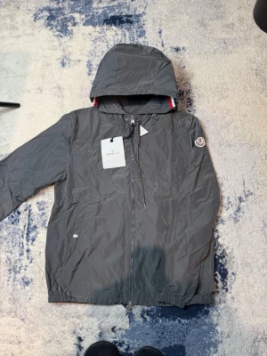 	Grå Moncler windbreaker - NFC funkar. inte använd. tags kvar