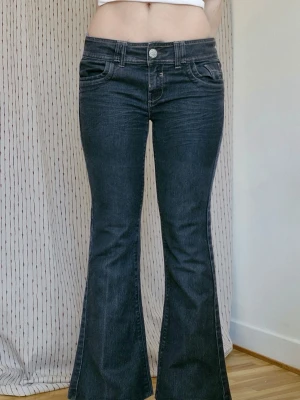 Lågmidjade bootcut-jeans från 2000-talet - Fantastiska lågmidjade jeans från Falmer 🖤 Vintage från tidigt 2000-tal! Köpta på Vinted, säljer då de tyvärr är för korta för mig. Svarta/ mörkgrå med coola knappar och broderade fickor :) Passform: flare  Midja: 41 cm x2 Grenhöjd: 22 cm Innerbenslängd: 71 cm