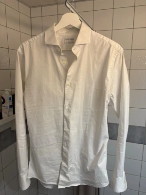 Vit skjorta från Tiger of Sweden - Klassisk vit skjorta från Tiger of Sweden i bomull. Skjortan har lång ärm, knappar framtill och en stilren, tidlös design som passar till allt. Perfekt för dig som gillar enkel och clean stil. Passar M/S. Använd ett fåtal gånger