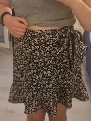 Svart blommig kjol med volang - Supersöt svart kjol med vitt blommönster och volangkant. Skriv vid intresse.❤️