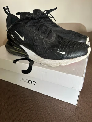 Nike Air Max 270 svarta sneakers - Nike Air Max 270 sneakers i svart. Små vita loggor på sidan och tå, samt röd detalj under sulan. Skön passform. Originalkartong. 