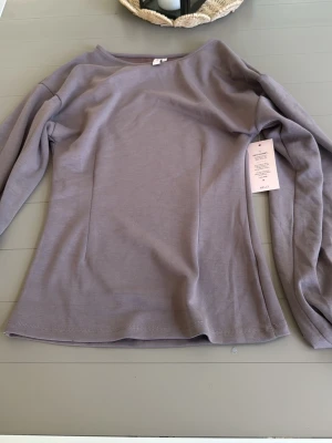 Ljuslila långärmad topp från H&M - Säljer en stilren ljuslila långärmad topp från H&M. Toppen har en enkel, rak passform och är tillverkad i mjuk bomull. Perfekt att matcha med jeans eller kjol för en clean look.
