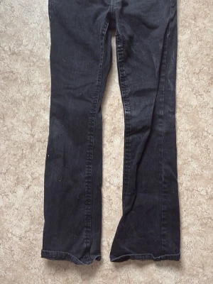 Svarta bootcut jeans från Perfect Jeans - Snygga svarta bootcut jeans från Perfect Jeans i storlek 38. Klassisk femficksmodell med bälteshällor och knappgylf. Jeansen har en rak passform med lätt utsvängda ben och är tillverkade i ett mjukt denimtyg.