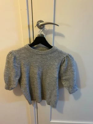 Gina Tricot Young stickad tröja med puffärm – stl 146/152 -   Fin grå stickad tröja från Gina Tricot Young i storlek 146/152. Modellen har trendiga puffärmar och en bekväm passform. Tröjan är i mycket bra skick och utan fläckar eller hål. Kommer från rök och djurfritt hem.  