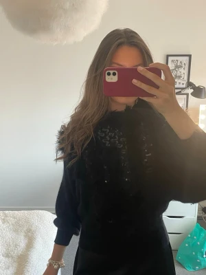 Svart tröja med paljetter - Säljer en svart tröja med paljettdetaljer framtill och fluffiga inslag. Tröjan har trekvartärmar och passar xs! Perfekt för dig som gillar att sticka ut lite extra med din outfit. Den är köpt i NYC så vet ej var den är ifrån 💕