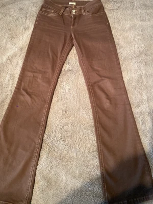 Low waist Bootcut Stitc Jeans Bruna - Bruna bootcut jeans med ljusa kontrastsömmar och klassisk femficksdesign. Jeansen har två bakfickor med dekorativa sömmar. Säljer dom pågrund av att dom inte kommer till användning och är lite långa på mig. Har använt dom ungefär 5 gånger💗 