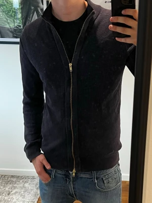 John Henric zip up cardigan - En riktigt fin mörkblå tröja ifrån John Jenric med heldragen dragkedja, den är i väldigt fin kvalité och i storlek M. Inga som helst skavanker som jag själv kan se!
