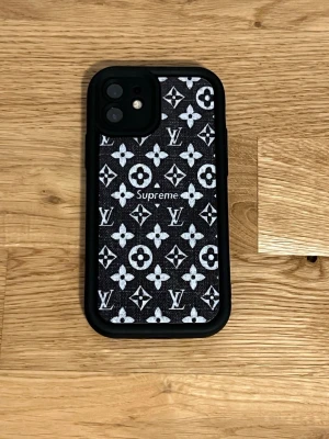 Mobilskal - Snyggt svart mobilskal med monogrammönster i vitt. Skalets material är troligtvis plast med en textil-liknande yta. Passar till iPhone och har en stilren, lyxig design som sticker ut.
