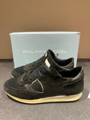 Philippe Model trainers - Snygga svarta philippe model trainers i bra skick. Skick 7/10.  Helt hets skicket är mycket bra men sulorna är lite slitna men inget som märks av vid användning. Tån på höger sko är också lite sliten (se bild) Stor 40 strl. Passar 41,42.  Box medföljer inte!