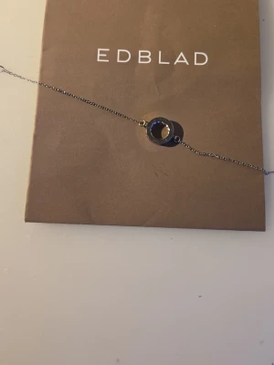 Silverfärgat armband från Edblad - Snyggt och stilrent armband från Edblad i silverfärgad metall. Armbandet har en tunn kedja och ett runt, polerat hänge i mitten. Perfekt för dig som gillar minimalistisk design och vill ha ett smycke som passar till många olika stilar.