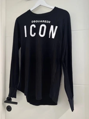Svarta Dsquared2 tröjor med tryck - Två svarta tröjor från Dsquared2. Ena har stort vitt 'ICON'-tryck och Dsquared2-logga framtill, lång ärm och rund hals. Den andra har Dsquared2 i rött broderat framtill, klassisk sweatshirtmodell med ribbade muddar. Perfekta för en trendig streetwear-look.