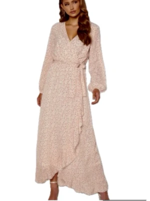 Maxi sommarklänning i XS. Sisters Point - Romantisk långklänning  i ljusrosa ton från Sisters Point med blommigt mönster och knytband i midjan. Klänningen har v-ringning och långa ärmar med lätt puff. Perfekt för dig som gillar romantiska och feminina detaljer. Aldrig använd🤷‍♀️