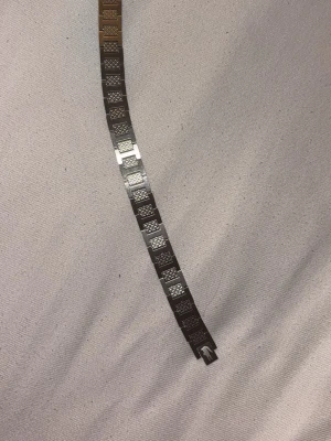 Silvrigt länkarmband i metall - Snyggt armband i silverfärgad metall med rektangulära länkar. Varje länk har ett graverat mönster som ger en cool och unik look. Perfekt för dig som gillar stilrena accessoarer med lite edge. Länkarna är blanka och har en modern känsla.
