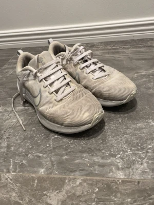 Vita Nike sneakers med mesh - Säljer ett par vita Nike sneakers med klassisk swoosh på sidan. Skorna har meshmaterial som ger bra ventilation och en lätt känsla. Lågt skaft och snörning framtill. Yttersulan är vit med mönster för extra grepp. Perfekt för dig som gillar sportig stil.