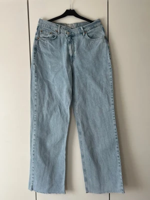 Ljusa blå jeans - Ljusa blå jeans från Stradivarius med vida ben och rå kant längst ner. Knäppningen är asymmetrisk vilket bidrar till en bra figurnära passform. Klassisk femficksdesign och hög midja💕💕