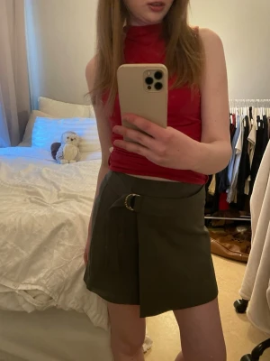 Röd croppad polotopp - Snygg röd croppad polotopp med ärmlös design. Toppen har en hög hals och sitter tight mot kroppen för en modern look. Perfekt att matcha med kjol eller jeans för en trendig outfit.