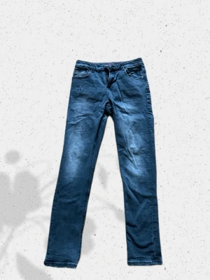 Mörkgrå jeans  - Snygga mörkgrå jeans med raka ben och klassisk femficksmodell. Jeansen har subtila slitningar framtill och kontrastsömmar. Passar perfekt till en avslappnad streetstil. Materialet är troligtvis bomullsdenim.