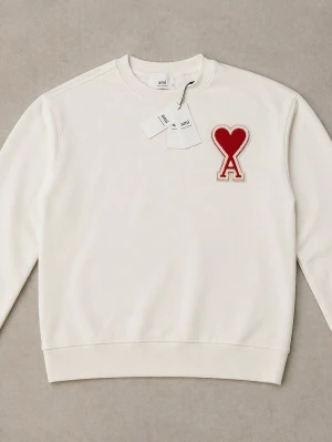 Ami Paris Sweatshirt 🤍❤️ - Vit sweatshirt från Ami Paris med rund hals och ribbade muddar. På bröstet sitter en stor röd hjärtdetalj med bokstaven A i chenille-tyg. Tröjan är i mjuk bomull och har en clean, stilren look som sticker ut med den ikoniska loggan. Storlek L-XL