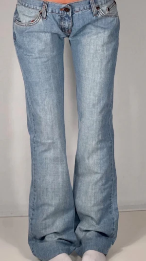 Ljusblå bootcut jeans - Säljer ett par ljusblå bootcut jeans med låg midja och klassiska fem fickor. Jeansen har en avslappnad passform och är tillverkade i denim med lätt slitning. Perfekta för en casual och trendig look. Har ett litet märke längst ner vid benet! Skulle aäga strl xs/s