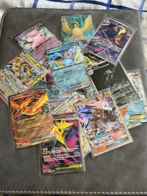Samling Pokémonkort GX och EX - Säljer en samling Pokémonkort med flera GX och EX-kort, bland annat Charizard, Lapras, Clefairy och Lycanroc. Korten har färgstarka illustrationer och är skyddade i plastfickor. Perfekt för dig som vill utöka din samling eller byta med vänner.