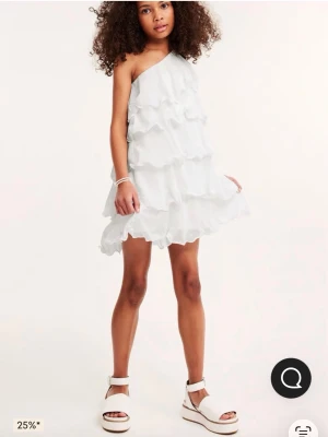 Vit oneshoulder volangklänning - Säljer en vit kortklänning med oneshoulder-design och flera lager volanger. Klänningen har en luftig och lätt form som ger en cool och trendig look. Perfekt för dig som gillar att sticka ut med detaljer och asymmetrisk stil. Perfekt till student eller skolavslutning!💞använd en gång så inga fläckar eller liknande men tvättas såklart vid köp🩷nypris 399kr, men säljs för 255kr