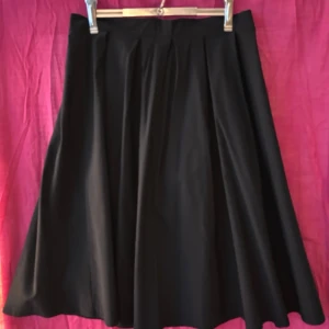 Daisy Dapper swing-kjol - Klassisk swingkjol i 50-talsstil från retro-märket Daisy Dapper. Strl L/40 (midja 80 cm). Dragkedja och knapp bak. Tillverkad i Sverige. Använd en gång. Har kostat 699 kr. 