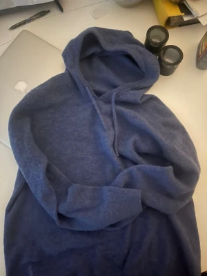 Mörkblå hoodie med huva - Mysig mörkblå hoodie med klassisk huva och dragsko. Tillverkad i mjukt material som känns skönt mot huden. Perfekt för en avslappnad och chill stil. Långa ärmar och ribbade muddar vid ärmslut och nederkant. PERFEKT FÖR VÅREN 🍃