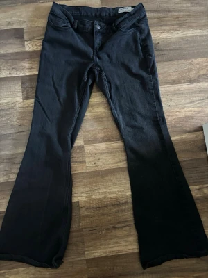 Svarta bootcut jeans Vero Moda - Snygga svarta bootcut jeans från Vero Moda med klassisk femficksmodell och knappgylf. Jeansen har en lätt utsvängd passform nedtill och är tillverkade i mjukt denimtyg. Perfekta för en trendig och avslappnad look. Medellåg midja. Något stor i midjan av tvättandet och lite blekta av tvätt då. Nypris ca 500. 
