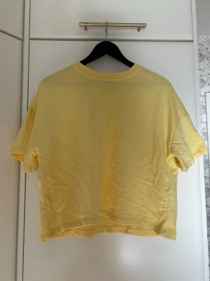 Gul t-shirt i bomull - En enkel och fräsch gul t-shirt. T-shirten har korta ärmar och rund halsringning.