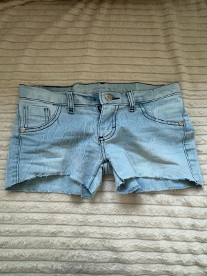 Lågmidjade jeansshorts  - Ljusblåa lågmidjade jeansshorts,  vet ej vart de är ifrån. Bra skick! Midjemått 35. 