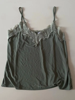 Grön linnetopp med spets från Amisu - Snygg grön linnetopp från Amisu. Har två små fläckar som inte syns mycket vid användning. 