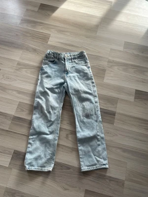 Ljusblå raka jeans - Säljer ett par ljusblå jeans med rak passform och klassisk femficksdesign. Jeansen har hög midja och är tillverkade i ett slitstarkt denimtyg. Perfekta för en avslappnad och trendig look.