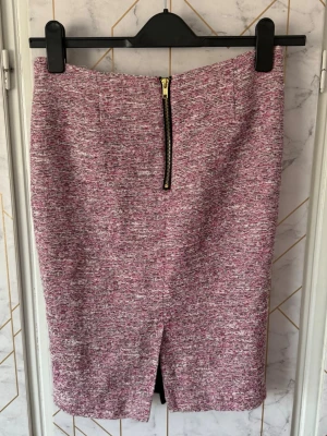 Rosa melerad pennkjol med dragkedja - Säljer en snygg rosa och vit melerad pennkjol med markerad dragkedja bak och liten slits. Kjolen har en rak, figursydd passform. Storlek 38 men passar även 36.