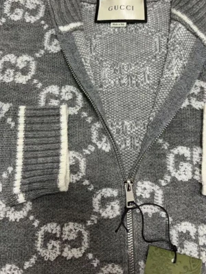 Grå ziptröja med GG-mönster från Gucci - Snygg grå ziptröja från Gucci med vitt GG-monogram över hela plagget. Tröjan har ribbade muddar och nederkant med vita detaljer samt hög krage. Tillverkad i mjukt stickat material som känns lyxigt och trendigt. Storlek S men passar xs också. Om du vill se mer bilder eller video då får du gärna skriva