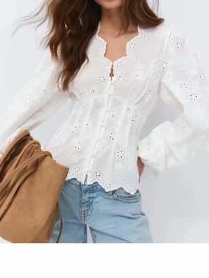 Vit broderad blus med puffärm - Söt vit blus från Gina med broderade blommor och knappar framtill. Blusen har lång puffärm, figurnära passform och vågig kant vid halsringningen. Helt slutsålt på hemsidan och i butik💗ändast testad 