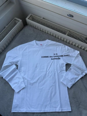 Comme des Garçons SHIRT x Supreme Long Sleeve – White - CDG SHIRT x Supreme collaboration long sleeve.  Clean white color with front print. Great streetwear essential piece.  Good condition.   SIZE M BUT FITS S